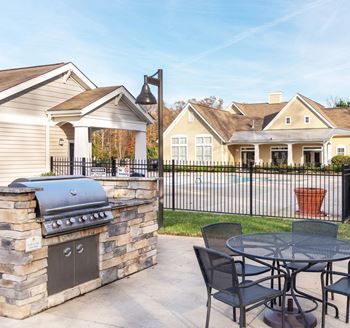a patio with a barbecue grill and a table and chairs